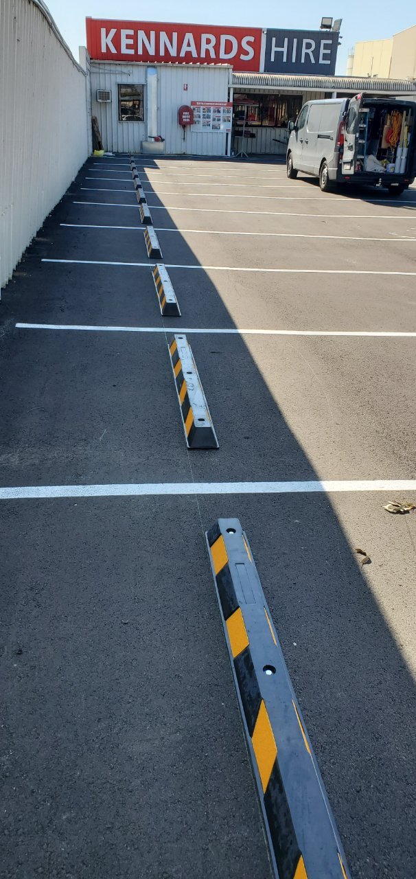 Black and yellow wheel stops installed along car park bays
